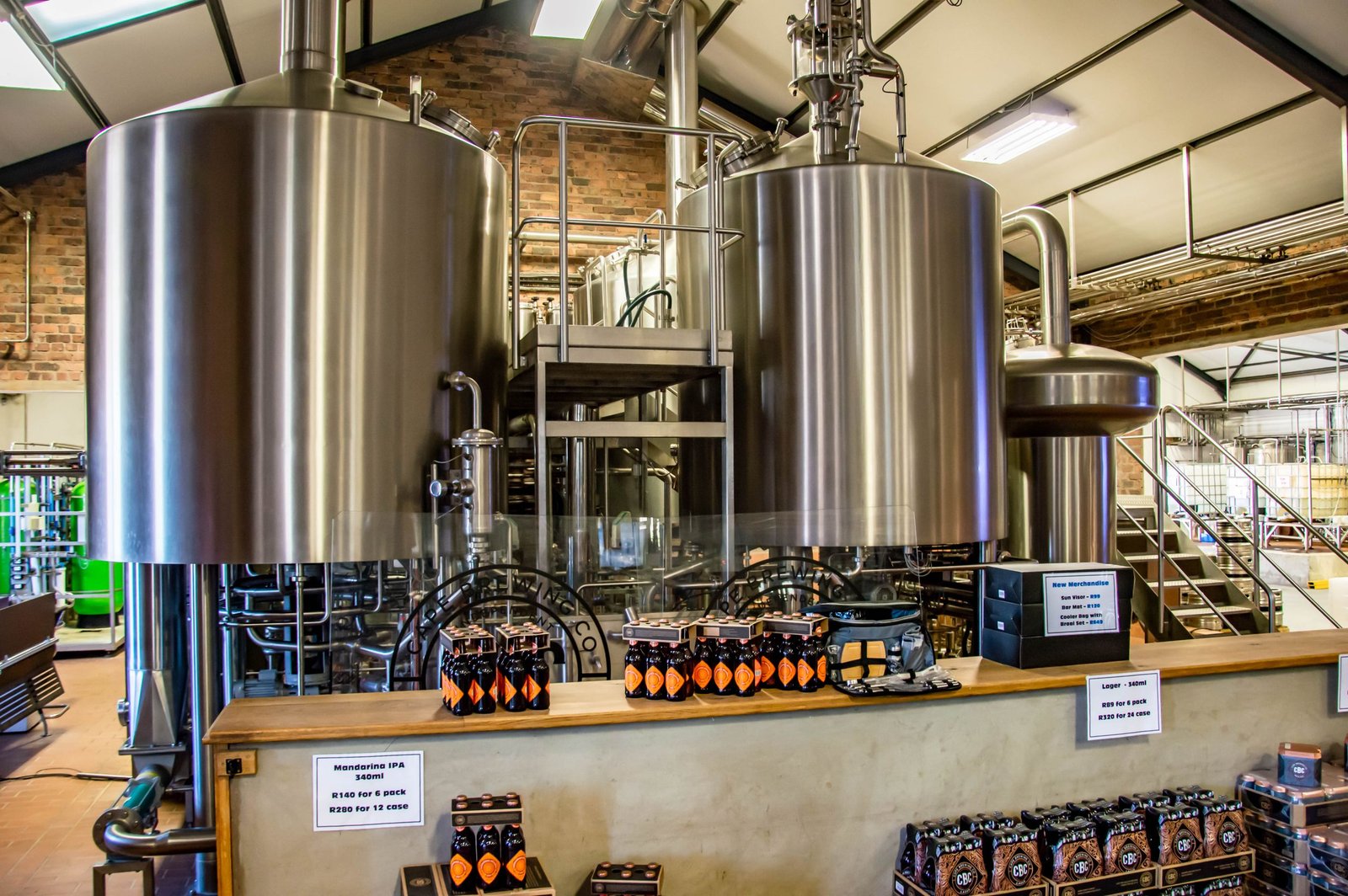 Interior of a brewery showcasing large stainless steel tanks and bottled beverages on display.