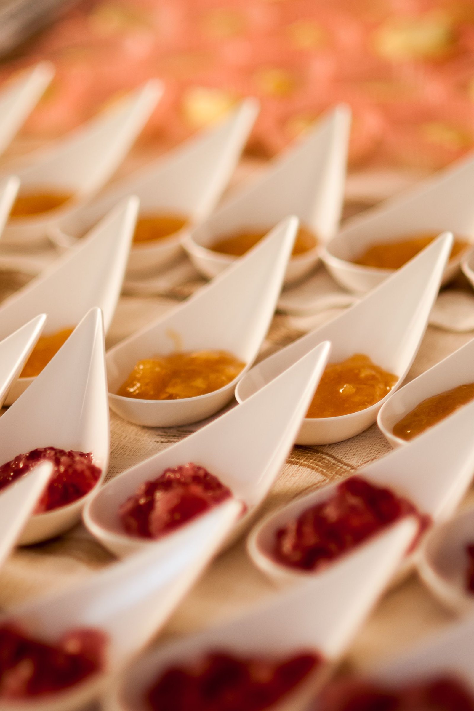 A close-up of gourmet jams in porcelain spoons arranged in rows, creating a colorful pattern.
