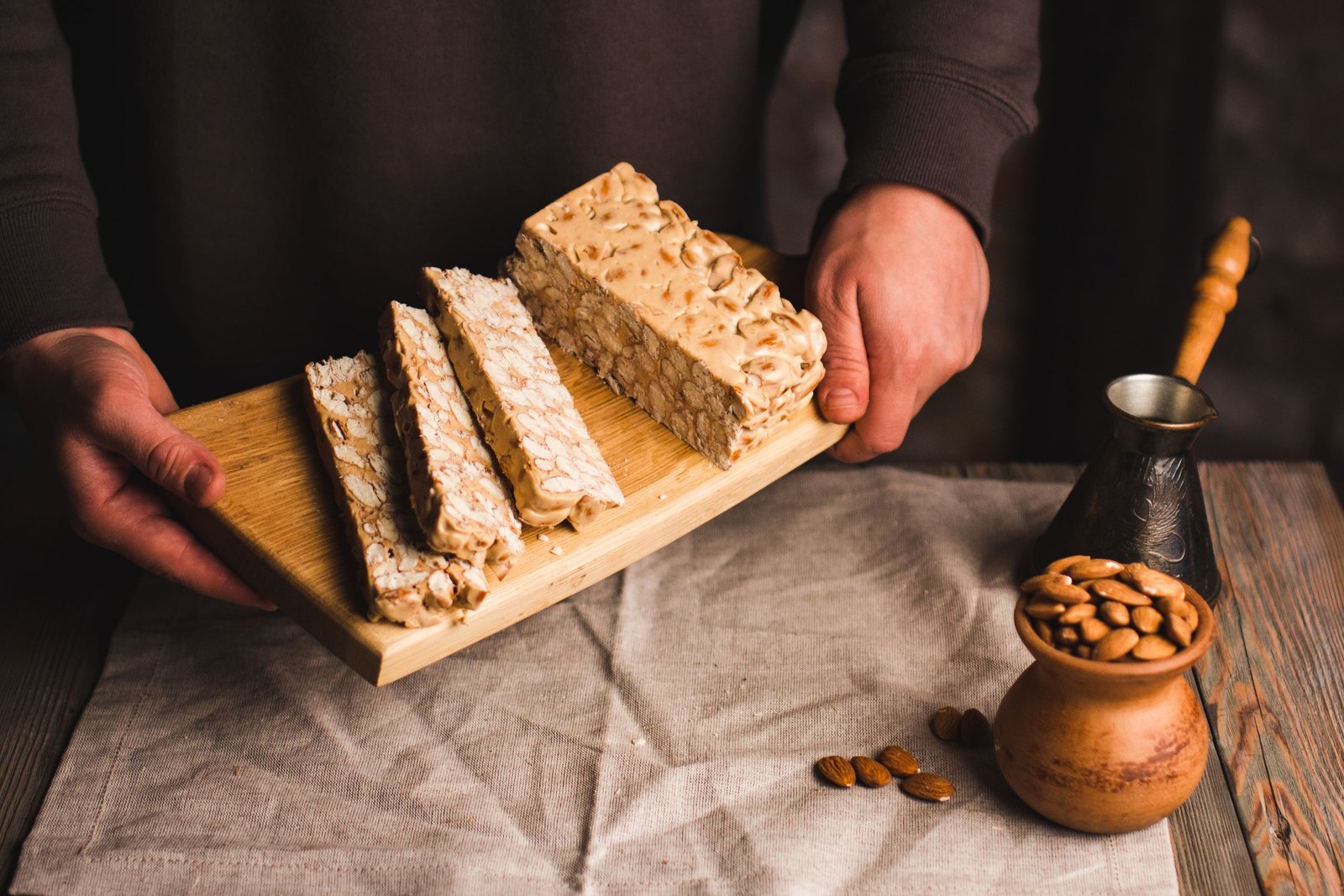 Almond nougat slices on a wooden board, showcasing a homemade dessert with almonds.