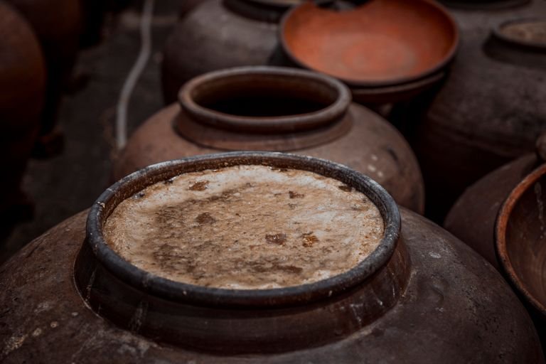 Close-up of rustic ceramic pots with visible fermentation, showcasing traditional pottery techniques.