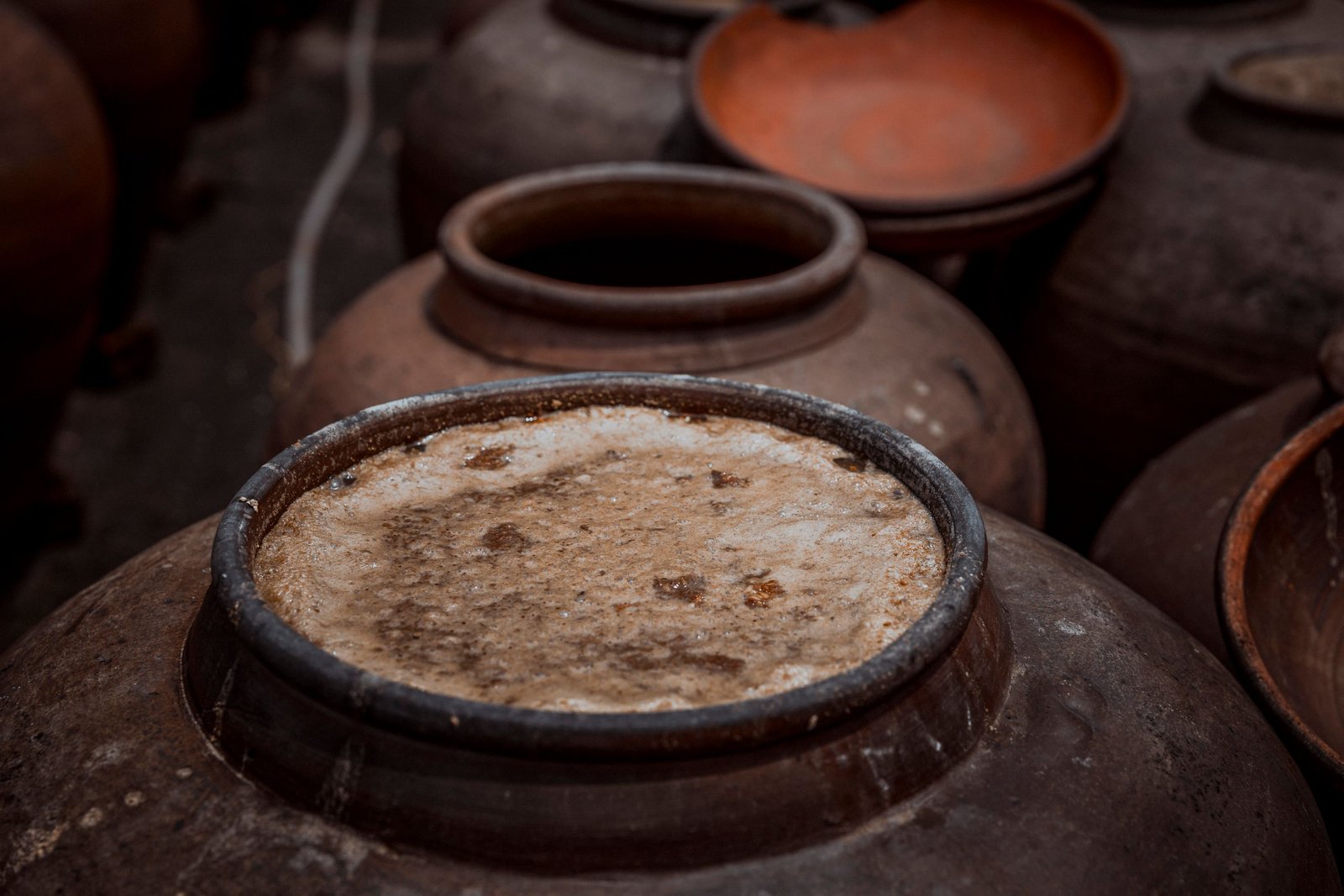 Close-up of rustic ceramic pots with visible fermentation, showcasing traditional pottery techniques.